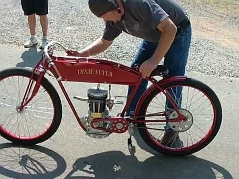 a man is working on an old style red bike with the engine attached to it