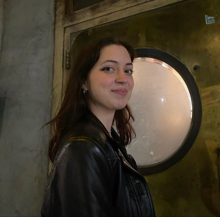 a woman is standing in front of a round mirror with her eyes closed and looking at the camera