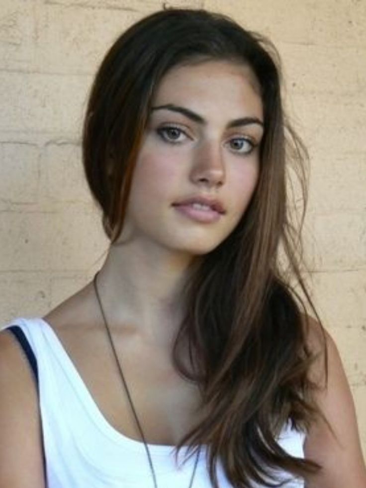 a woman with long brown hair wearing a white tank top