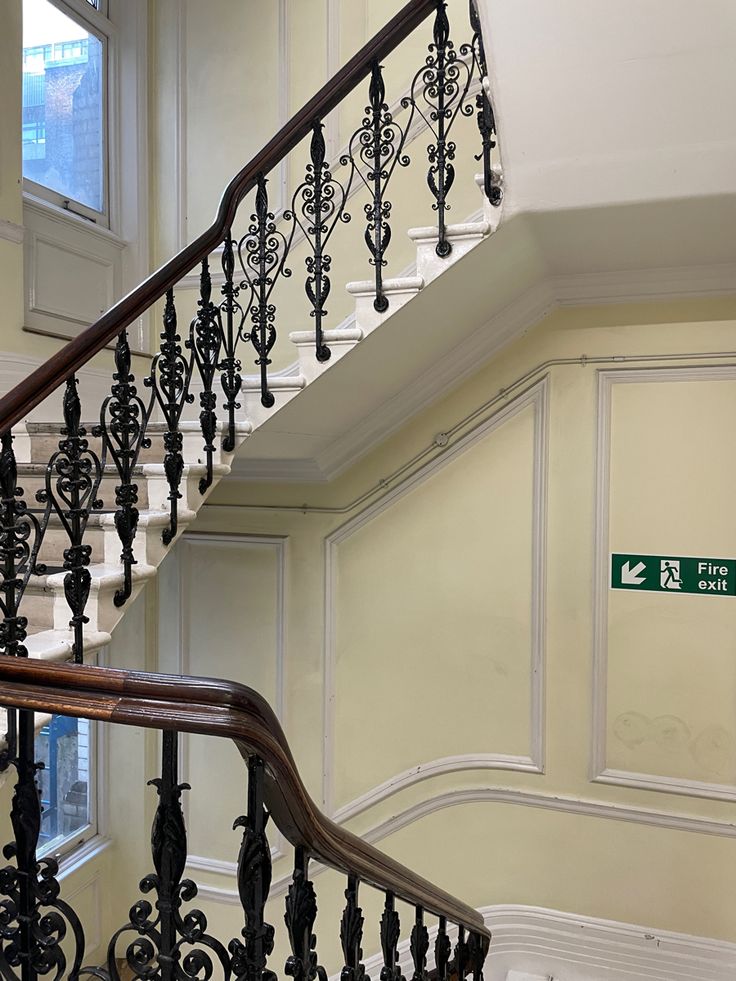 a staircase with wrought iron handrails and a green street sign on the wall