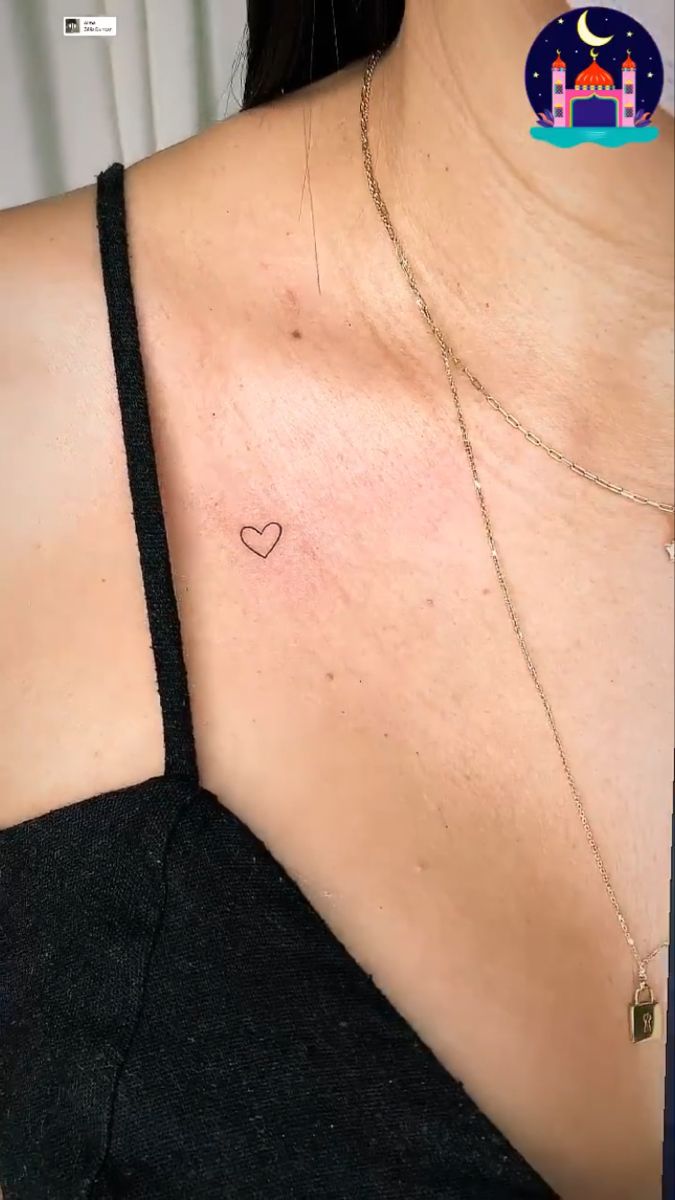 a woman's chest with a small heart tattoo on the left side of her chest