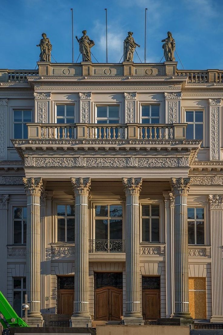 a large white building with statues on the top of it's roof and balconies