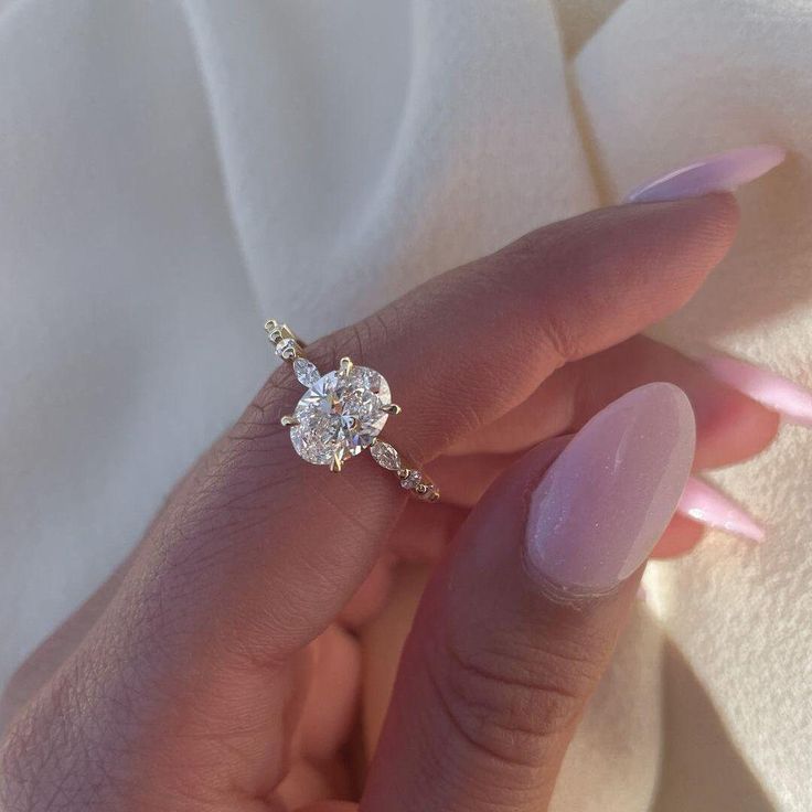 a woman's hand holding an engagement ring in her left hand, with the center diamond