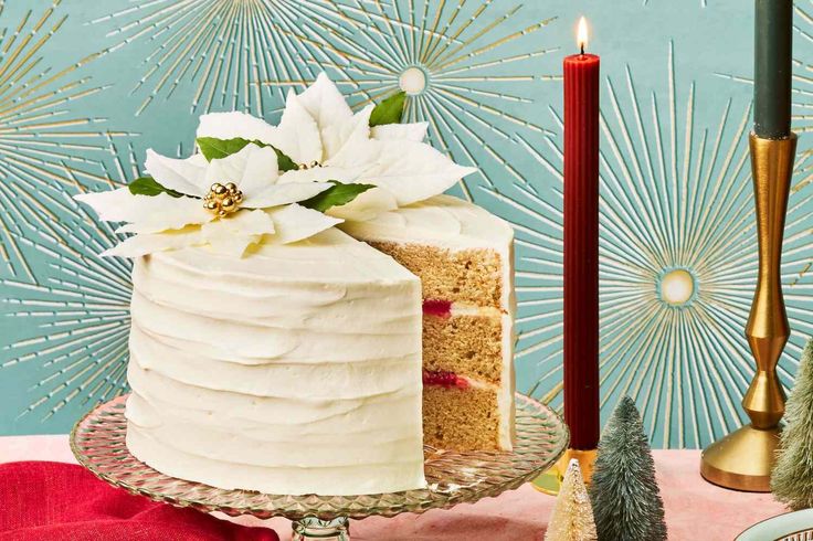 a white frosted cake sitting on top of a table next to a lit candle