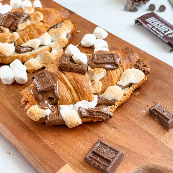 a wooden cutting board topped with chocolate and marshmallows