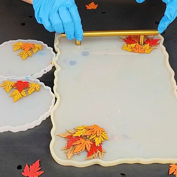 a person in blue gloves is making fall leaves out of cookie dough