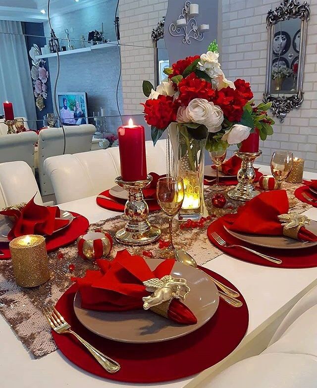 the table is set with red napkins, silverware and gold placemats