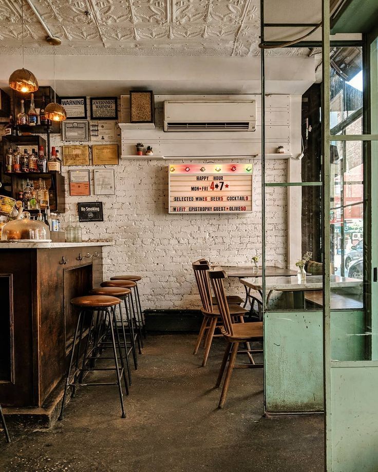 the interior of a restaurant with wooden tables and chairs, an old brick wall and exposed ceiling