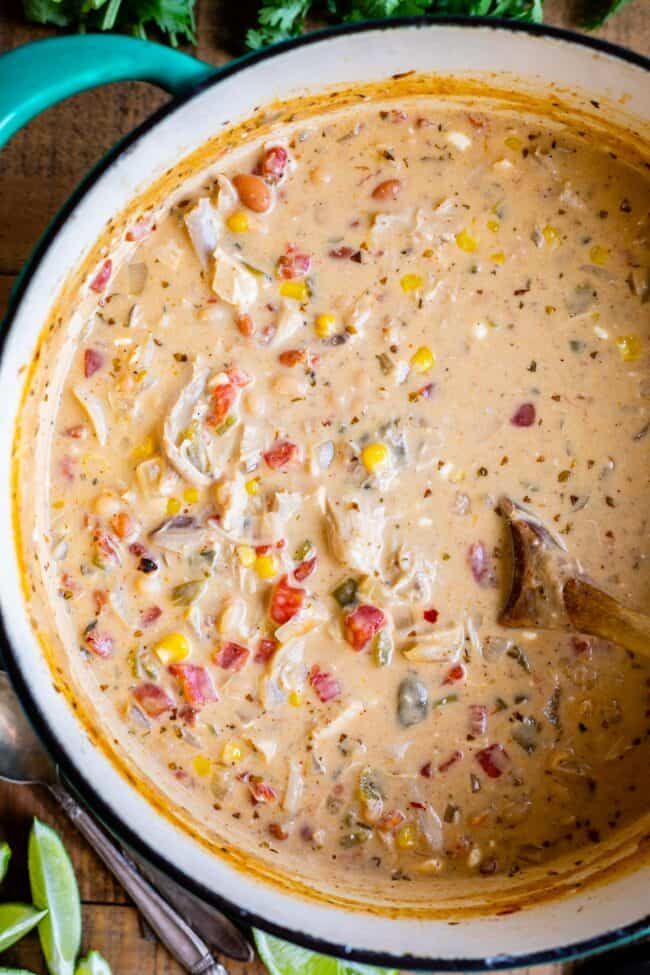 a bowl filled with soup sitting on top of a wooden table next to a spoon