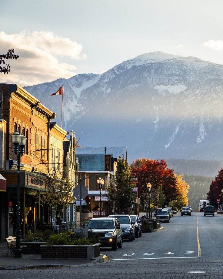 cars are parked on the street in front of buildings with mountains in the back ground