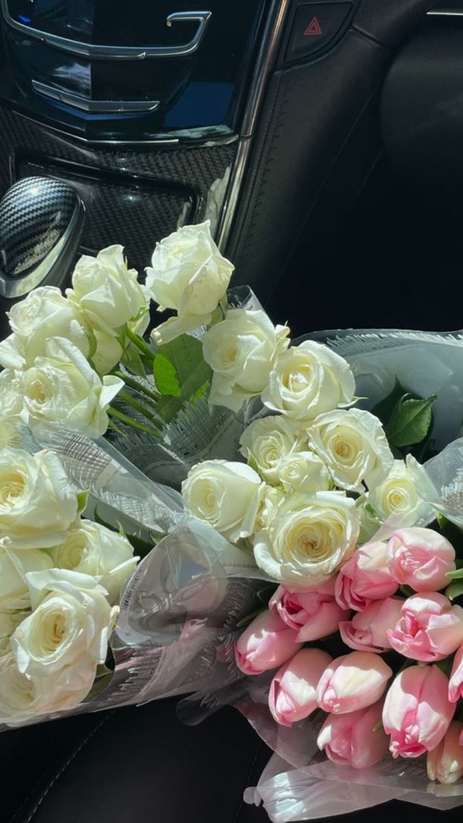 a bouquet of white and pink roses in the front seat of a car