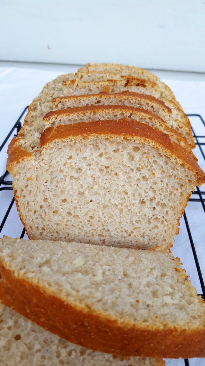 a loaf of bread sitting on top of a cooling rack next to slices of bread