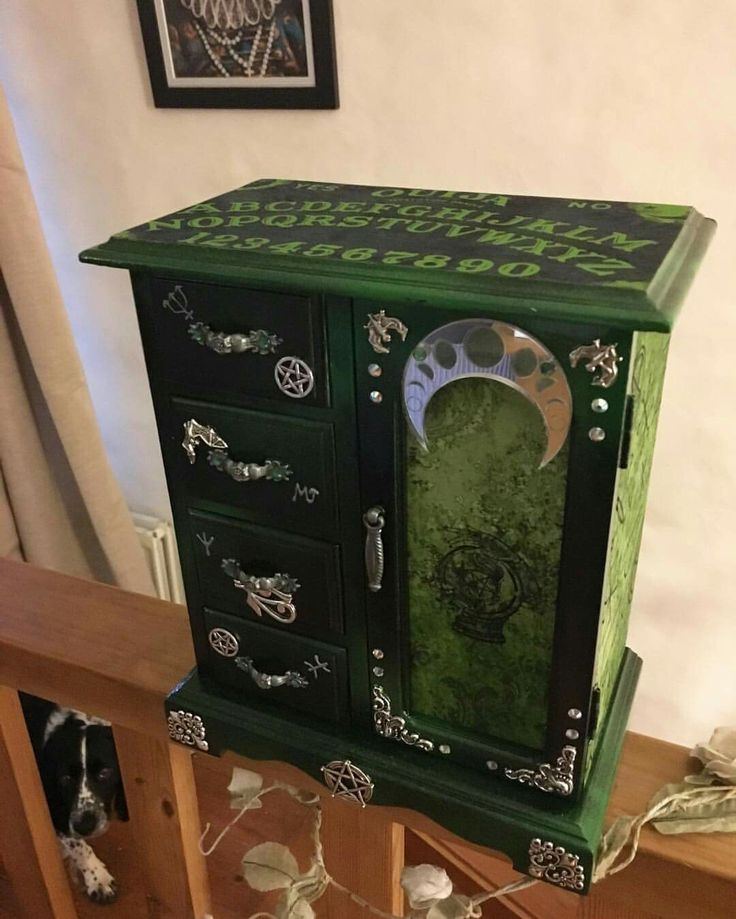 a green and black cabinet sitting on top of a wooden floor next to a wall