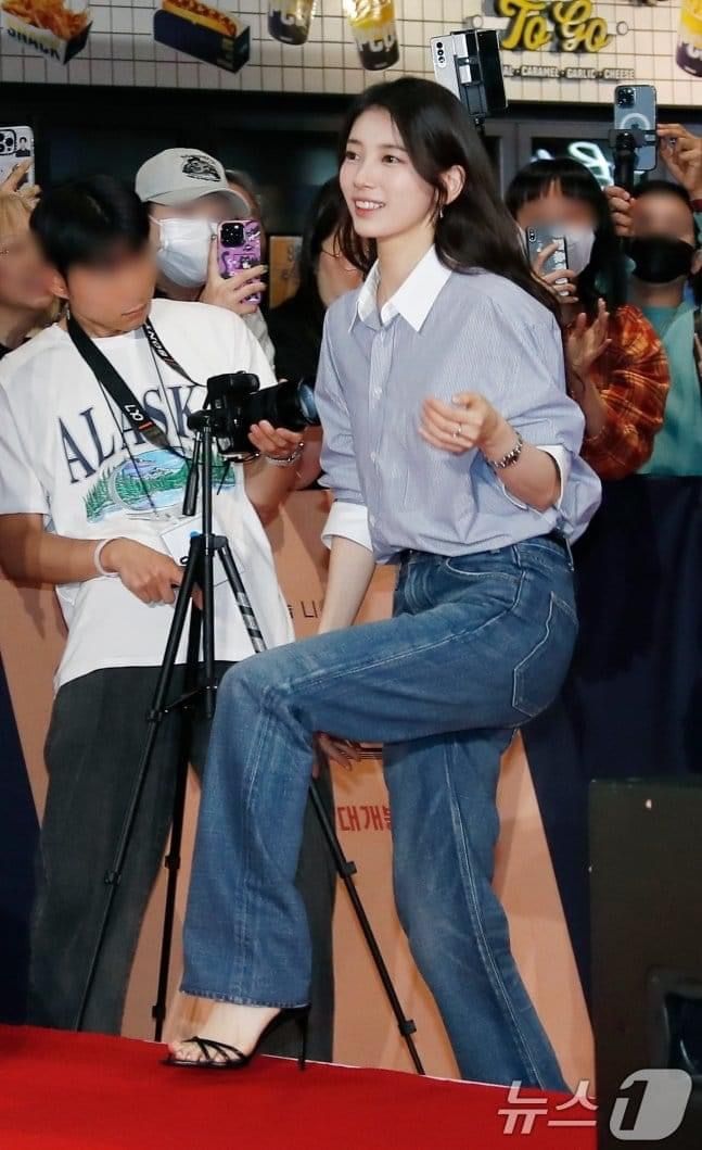 a woman standing on top of a red carpet next to a camera