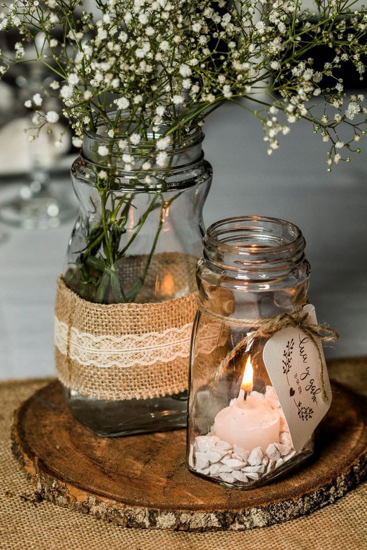 two mason jars filled with flowers and candles