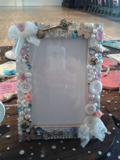 an ornate frame with buttons and pearls on the edge is sitting on a table covered in confetti