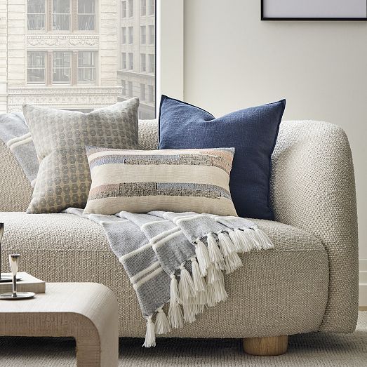 a couch with pillows and blankets on it in front of a window