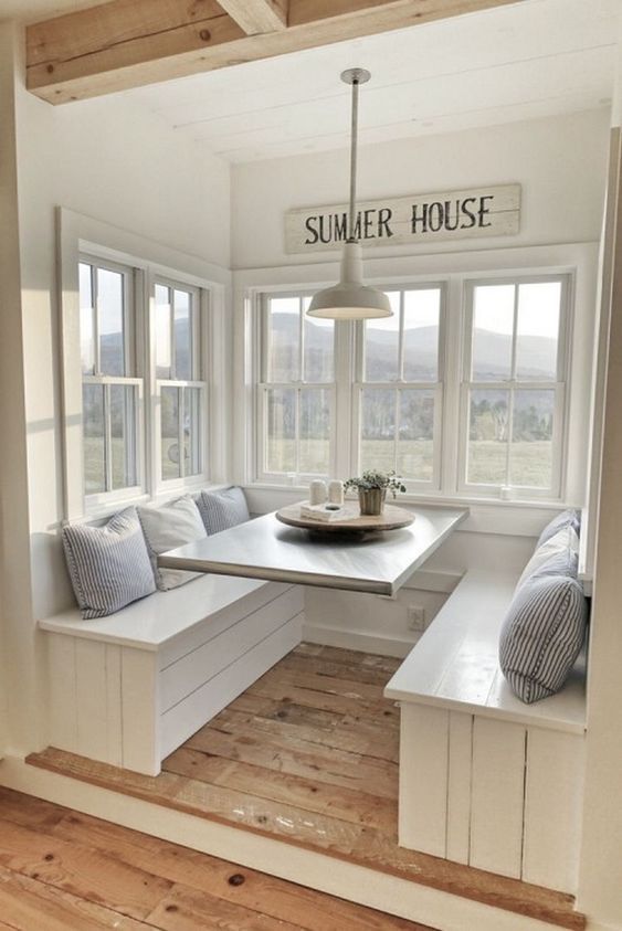 a window seat in the corner of a room with white walls and wood flooring