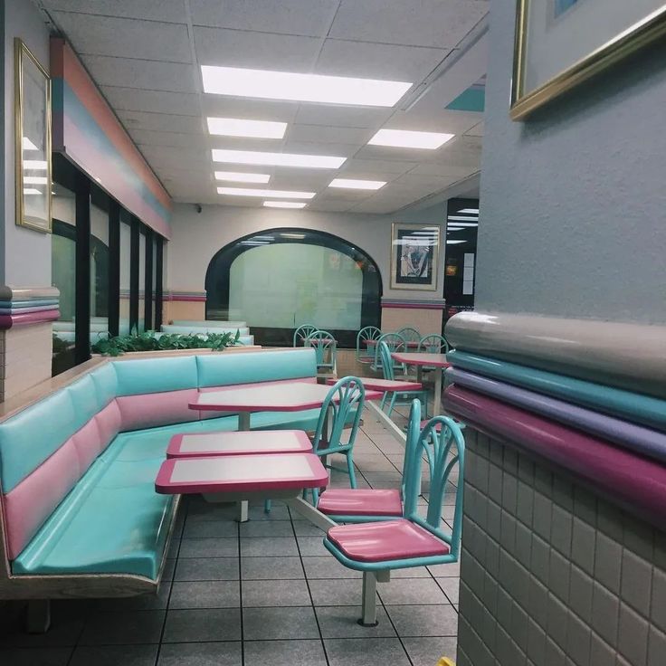 the inside of a diner with blue and pink booths, tables and chairs on tiled flooring