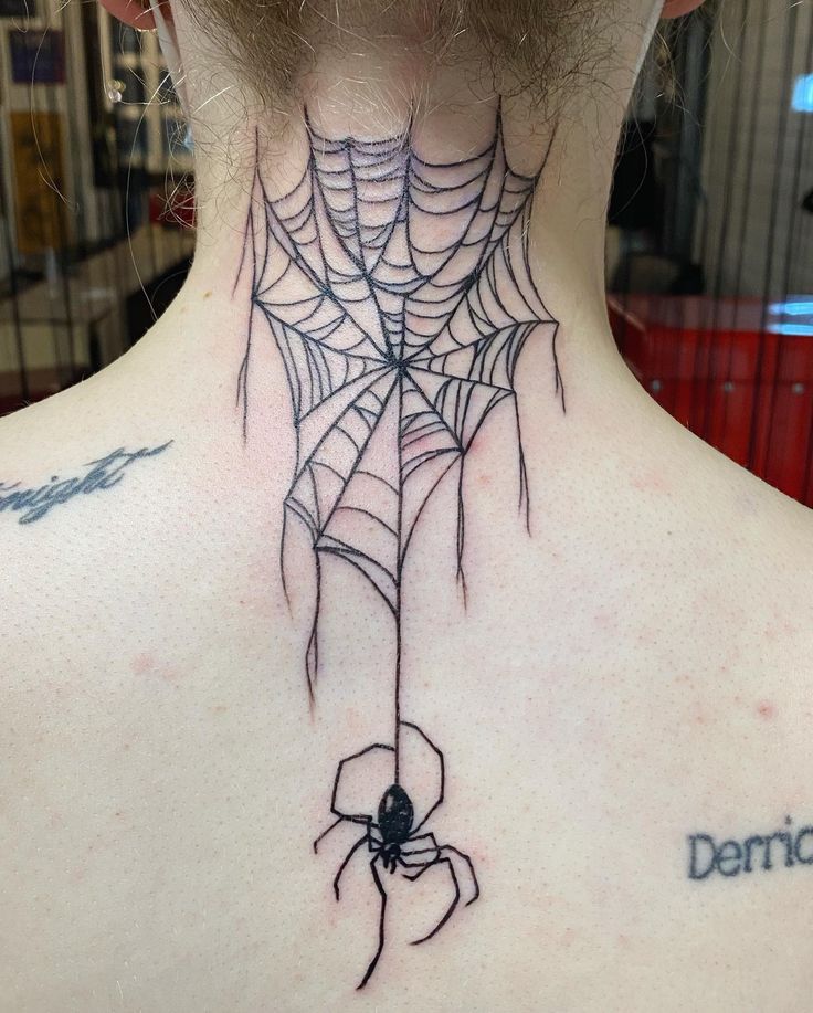 the back of a woman's neck with a spider web tattoo design on it