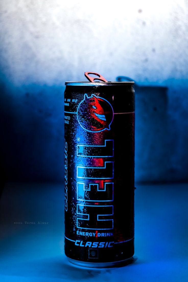 a can of energy drink sitting on top of a blue table next to a cup