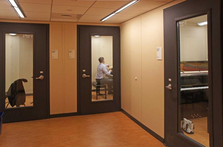 a man sitting at a desk in an empty room with two doors open to the other side