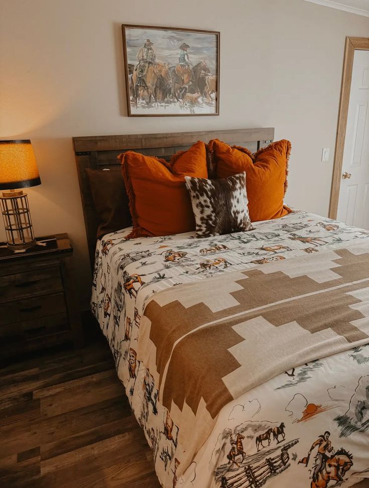 a bed with orange pillows and blankets in a bedroom next to a lamp on a nightstand