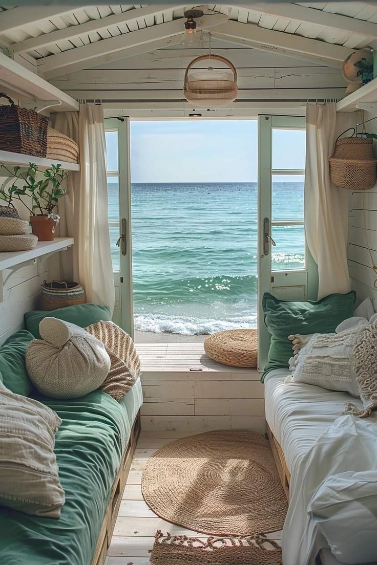 a room with two beds and an open window overlooking the ocean in front of it