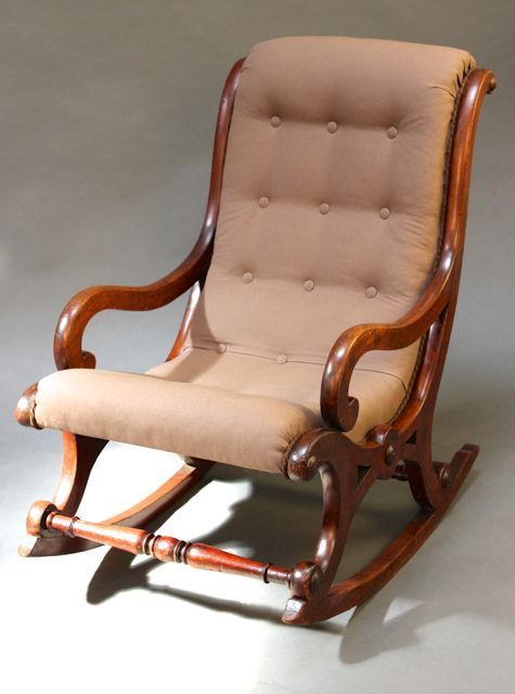 a wooden rocking chair with beige upholstered seat