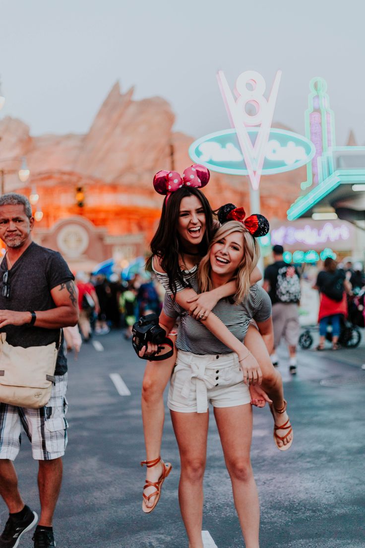 two women in mickey mouse ears hugging each other on the street at disneyland california adventure park