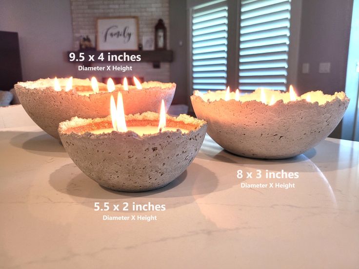 two concrete bowls with candles in them sitting on a counter