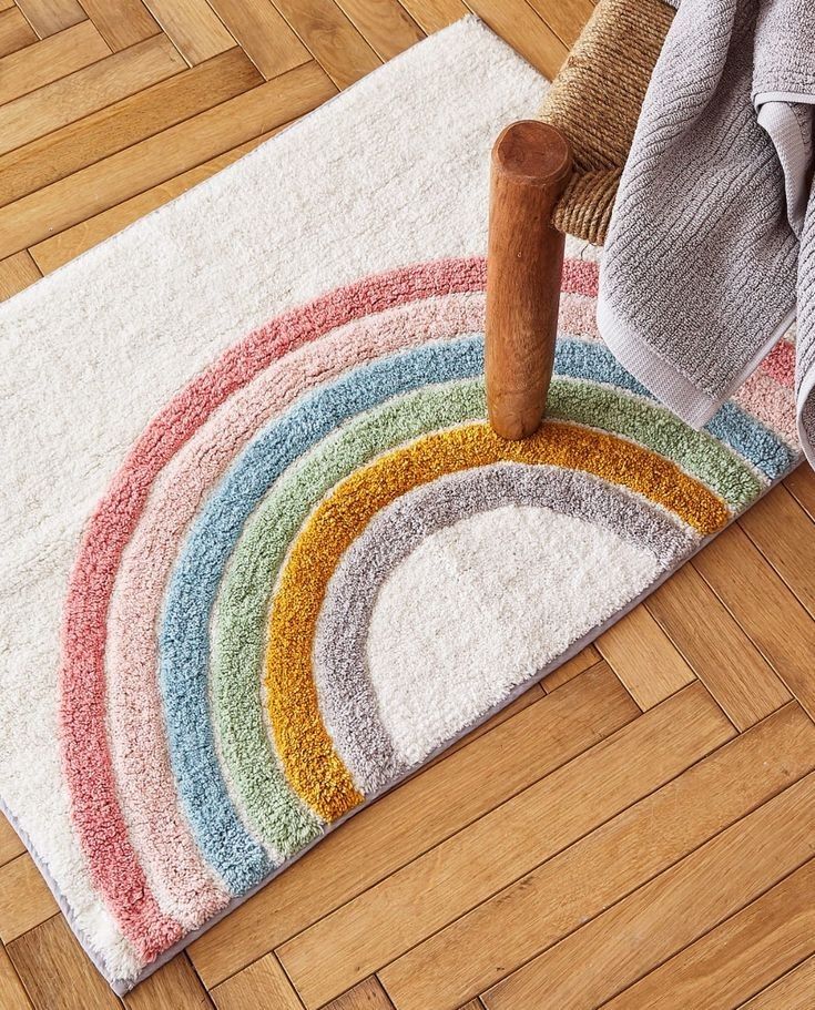 a rainbow rug is on the floor next to a chair with a wooden stick in it