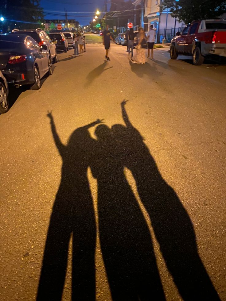 the shadow of two people holding hands in the street