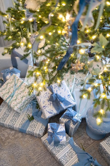 presents under the christmas tree are wrapped in blue and white paper with lights on them