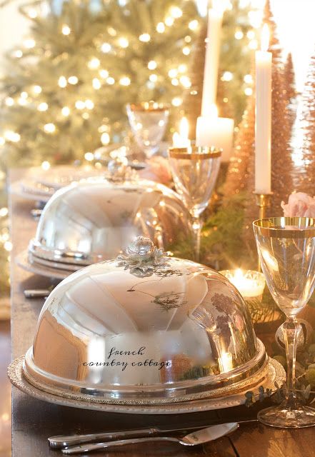 the table is set with silver dishes and candles for christmas dinner or brunch