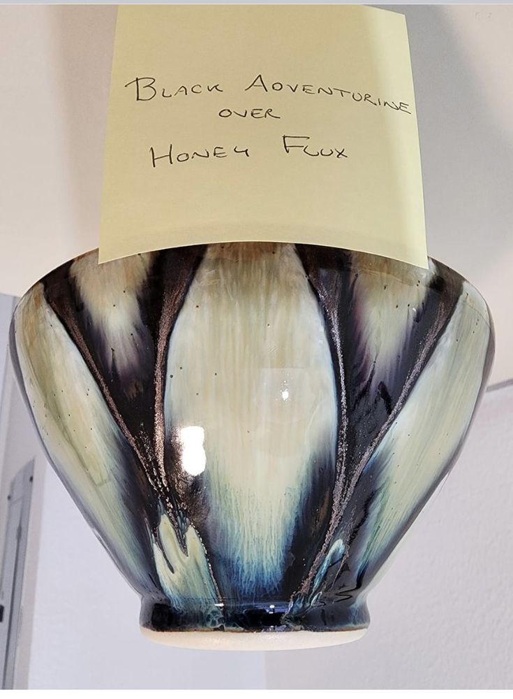 a black and white vase with a note attached to it's side hanging from the ceiling