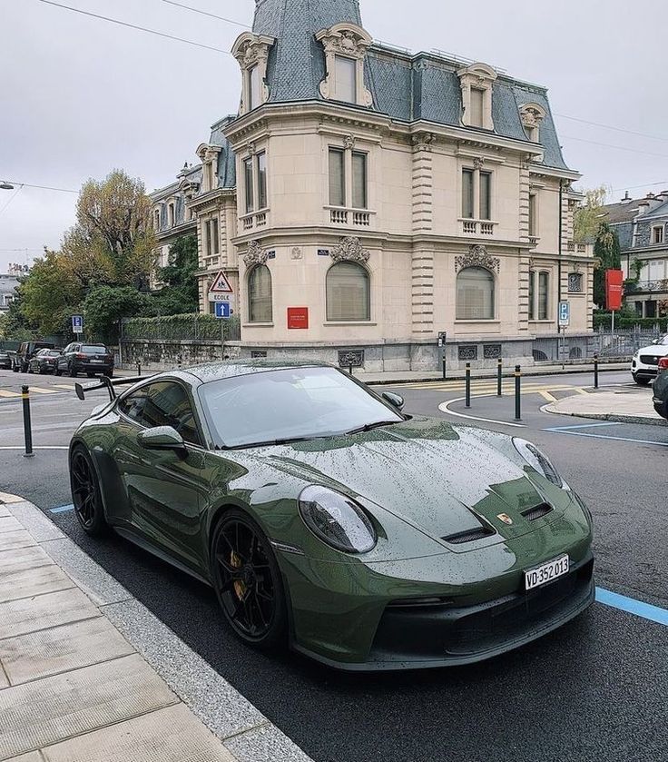 a green sports car parked on the side of the road in front of a building