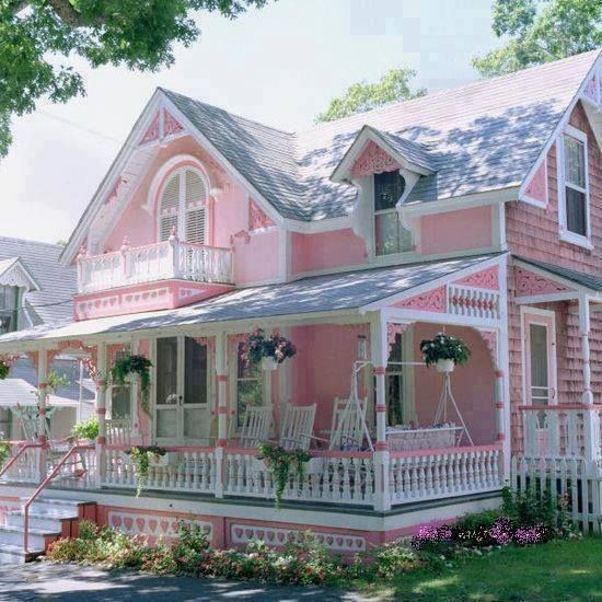 a pink house with white railings and flowers on the front porch is painted in shades of pink