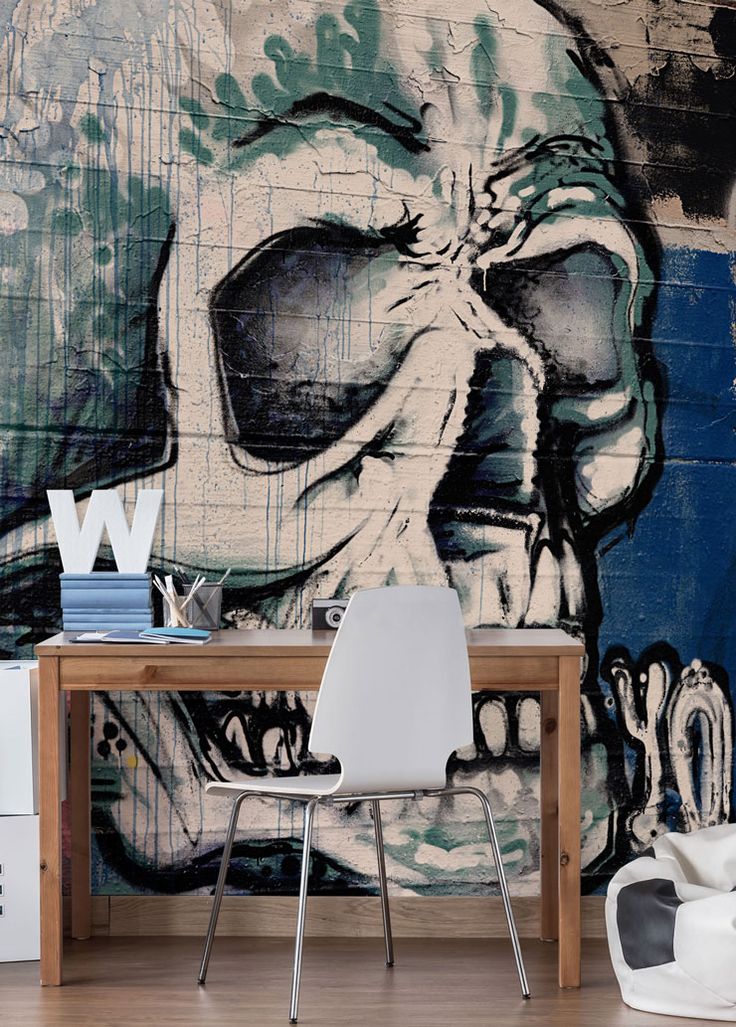 a wall mural with a large skull painted on it's side, next to a white chair and table