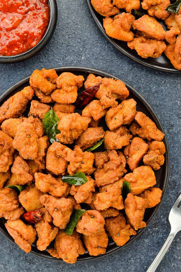 two black plates filled with fried chicken and sauce