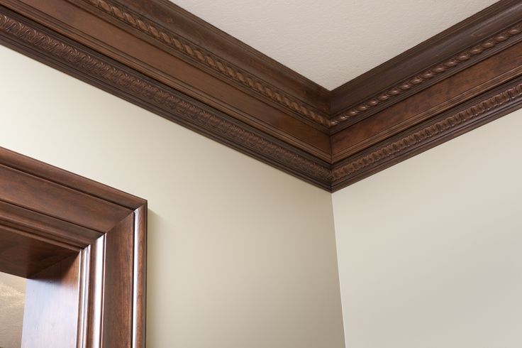 the corner of a room with a mirror and wood trimming on the wall above it