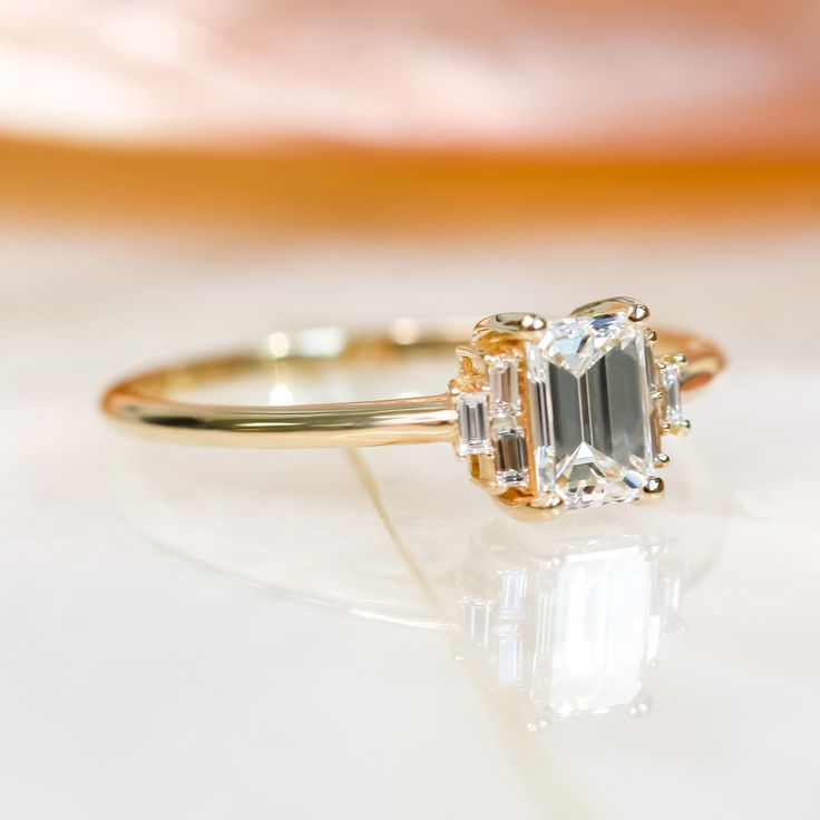 an engagement ring with a green and white diamond in the center, sitting on a marble surface