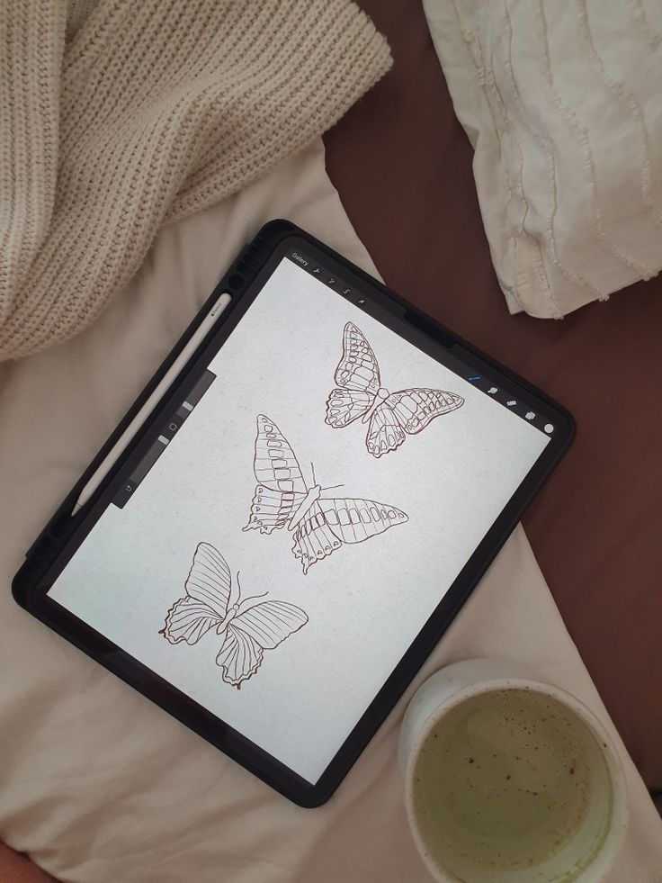 a tablet computer sitting on top of a bed next to a cup of coffee