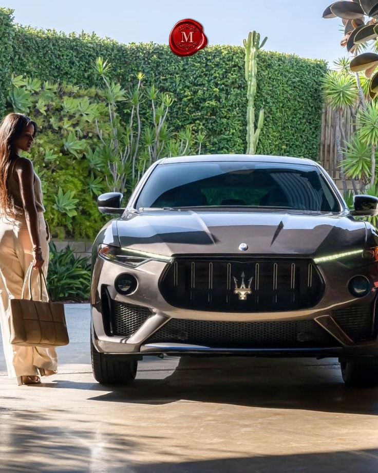 a woman standing next to a masera suv