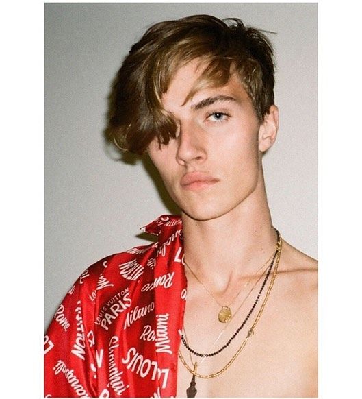 a young man wearing a red shirt and gold necklace