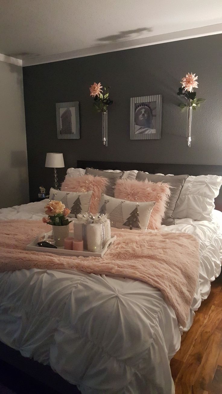 a bed with pink and white pillows on it in a bedroom next to two pictures