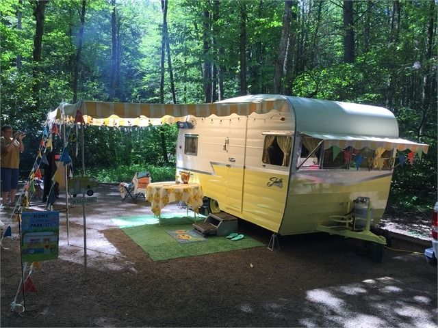 a yellow camper parked in the middle of a forest