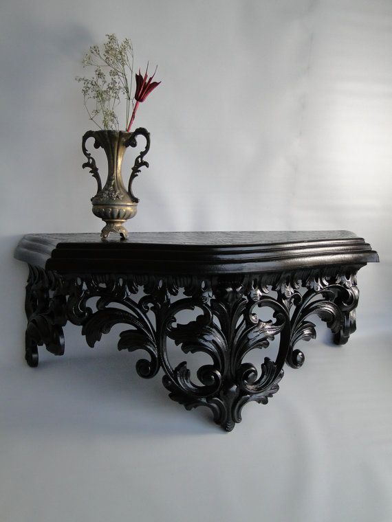 an ornate black table with a vase on top