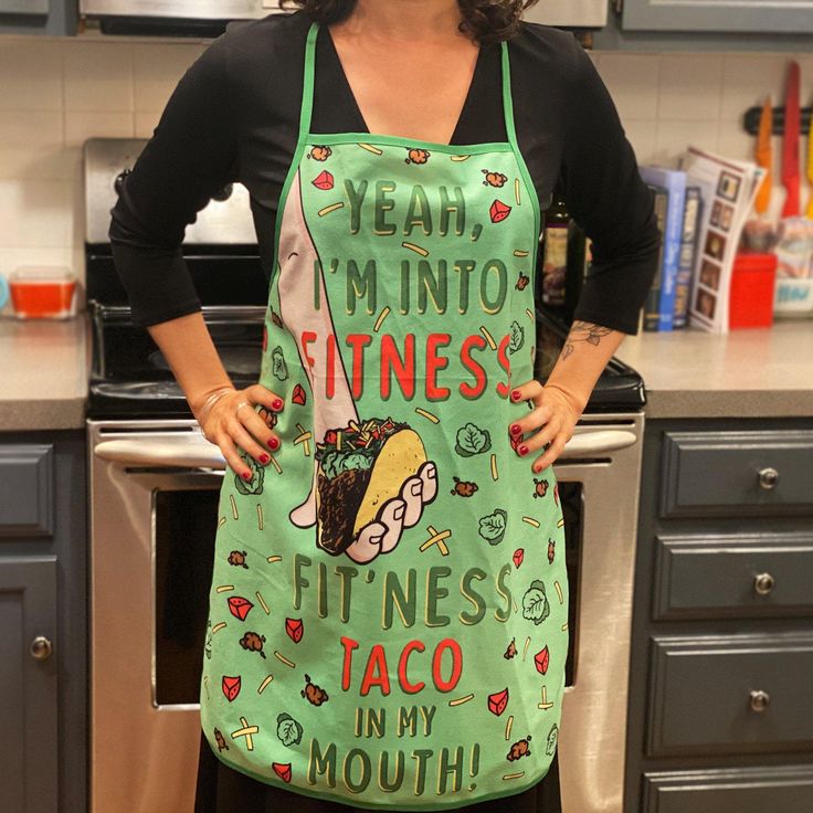 a woman standing in a kitchen wearing an apron that says yeah, i'm into fitness