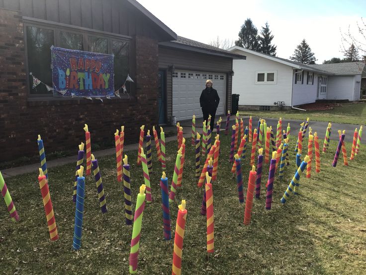 a man standing in front of a house with lots of colorful sticks sticking out of it